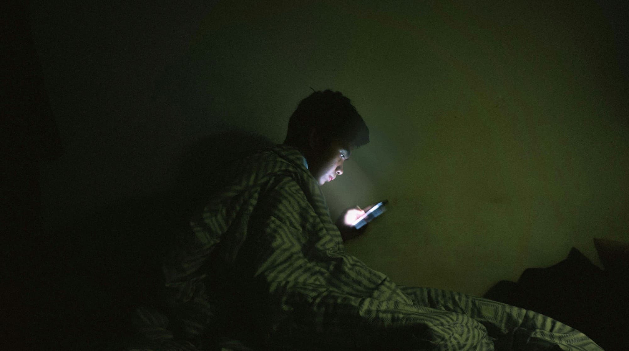 Étudiant éclairé par la lumière de son téléphone dans l'obscurité